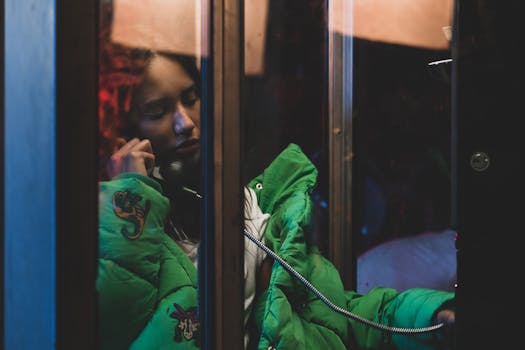 A woman in a green jacket uses a payphone in Los Angeles, CA.