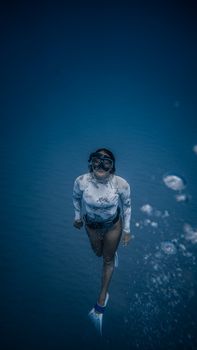 一位戴着护目镜、身穿泳衣的女性在深水中尽情享受，周身水花四溅