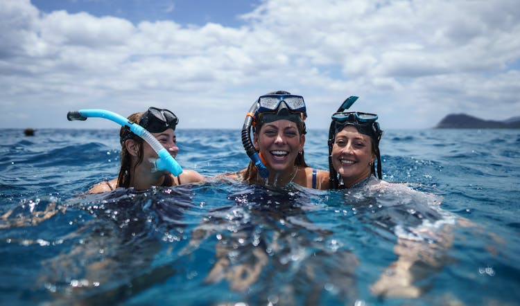 Group Of People In Mask And Snorkel Laughing In Water