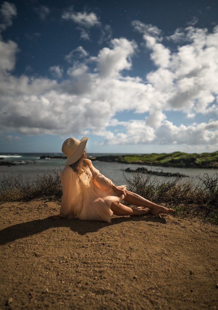 Woman In Silky Summer Dress Resting On Embankment