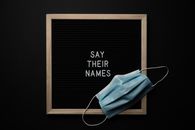 Medical mask on blackboard with wooden frame with white Say Their Names inscription placed on black background