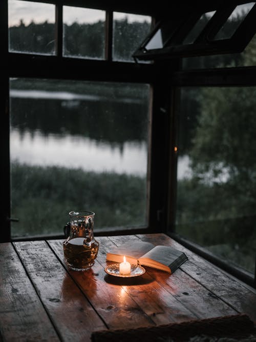 Lighted Candle and a Book on Wooden Table