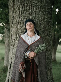 Woman in traditional attire meditates by a tree, embracing nature's serenity.