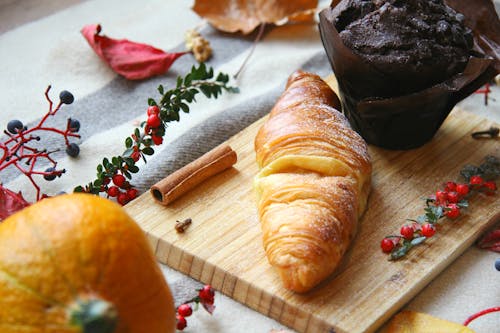 Free Croissant and a Chocolate Muffin on Wooden Chopping Board Stock Photo