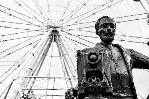 Grayscale Photo of a Statue and a Ferris Wheel