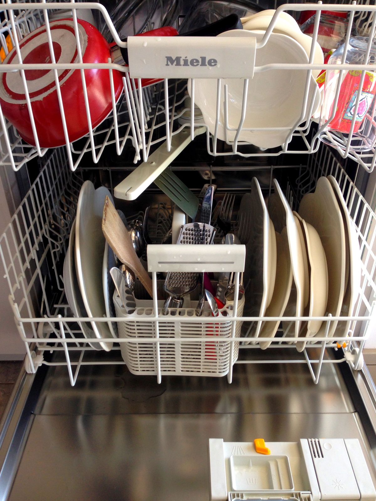 Open dishwasher rack filled with clean dishes and kitchenware after a wash cycle