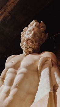 From below of relief statue of Zeus with naked torso against dark background