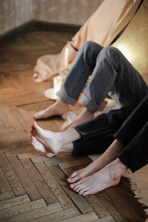 Free Person in Black Pants and White Socks Sitting on Brown Wooden Floor Stock Photo