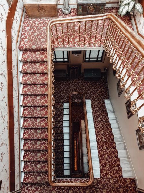 Free From above of aged stairway with red carpet and wooden railings in stylish house Stock Photo