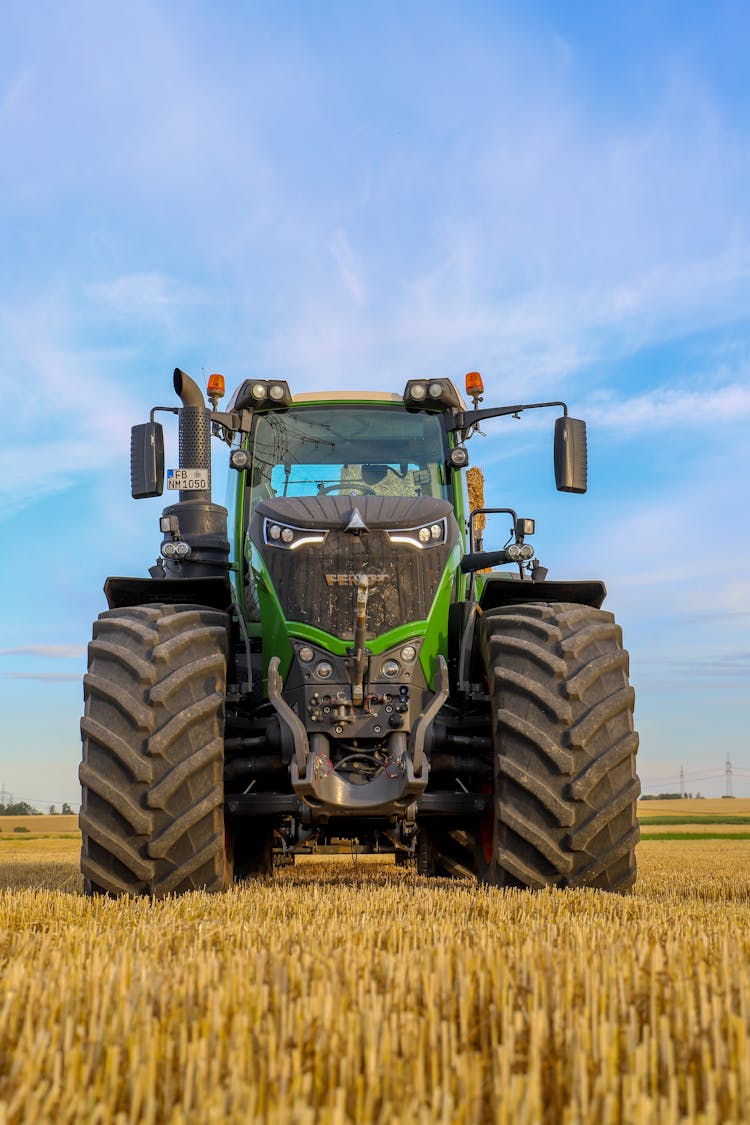 Green Tractor Parked On Hayfield