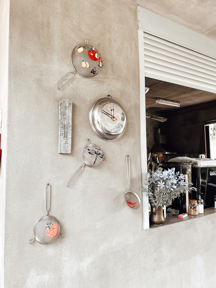 Kitchen Strainers Hanging On Wall Near Window With Rolling Shutters