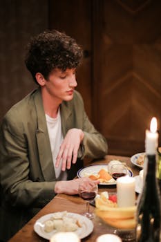Young man enjoying a candlelit dinner indoors, creating a warm and relaxed atmosphere.