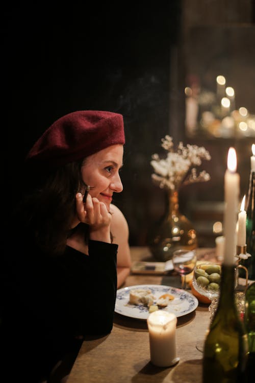 Woman in Black Long Sleeve Shirt Sitting Beside Table With Candles