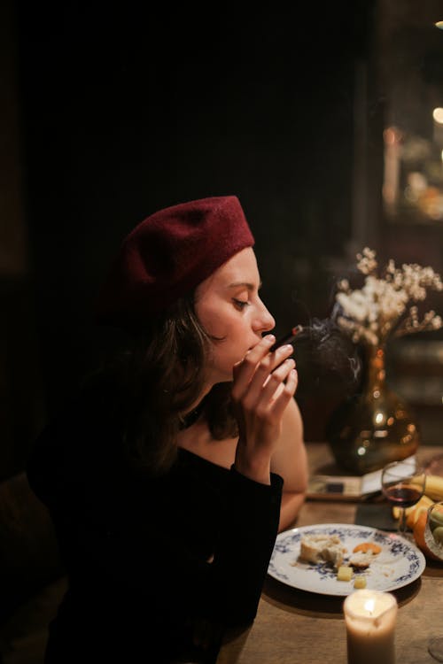 Woman in Black Long Sleeve Shirt and Red Knit Cap Sitting by the Table