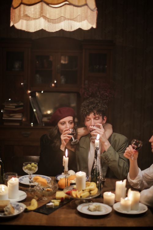 Free A warm and intimate candlelit dinner with friends, enjoying wine and a cozy atmosphere. Stock Photo
