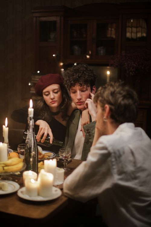 Free Intimate candlelit dinner scene with three friends enjoying an evening indoors. Stock Photo