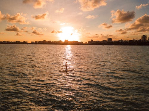 A Person Paddle Boarding at Sea during Sunset