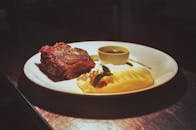 这道美食特写是牛排配土豆泥和酱汁，非常适合美食爱好者