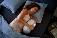 放松的女人躺在床上，抱着一个睡眠机器人，以求宁静的睡眠