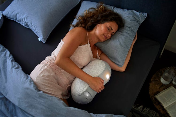 A Woman Hugging A Sleeping Robot While In Bed