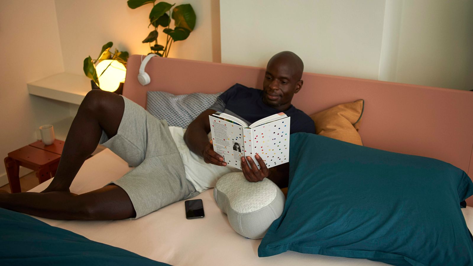 A man reading a book in a softly lit modern bedroom