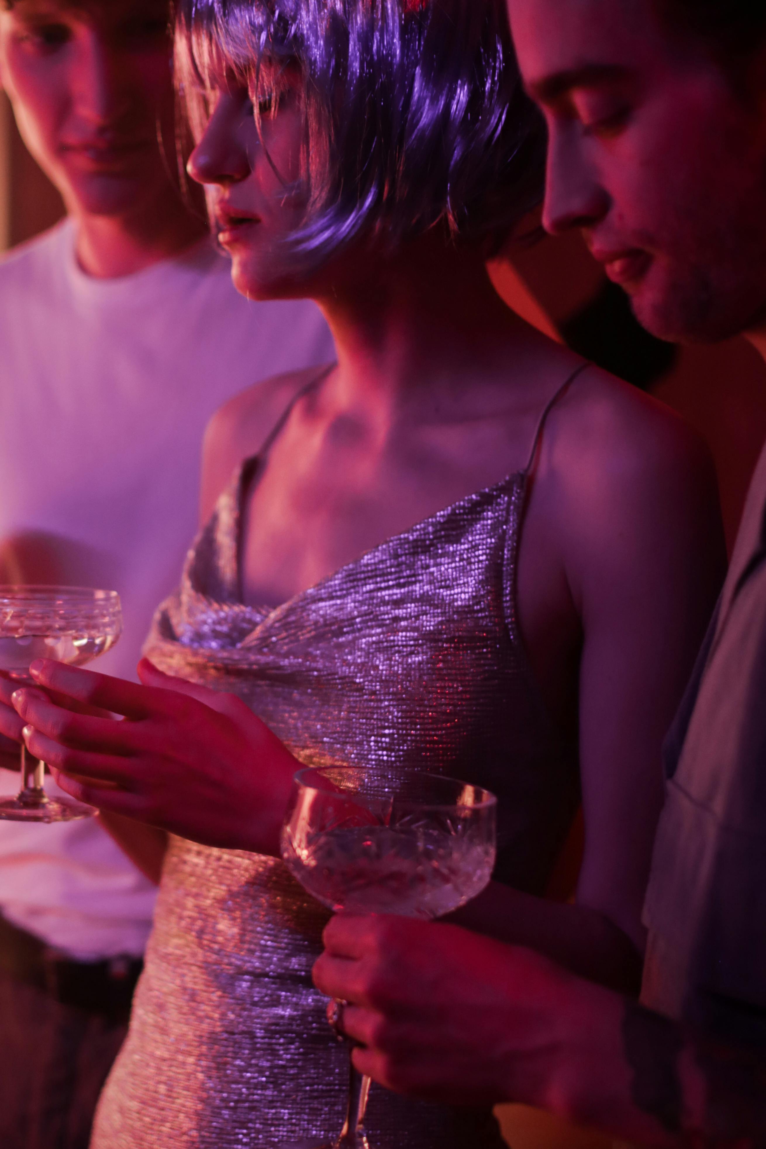 woman in gray spaghetti strap dress holding clear drinking glass