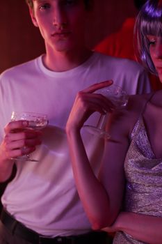 时尚的年轻人手持香槟杯，在热闹的夜生活氛围中尽情享受