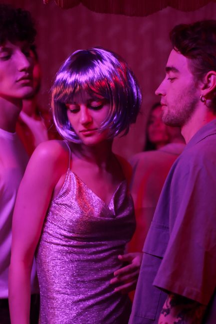 Young adults enjoying a vibrant party under colorful neon lights, featuring stylish attire and a playful atmosphere.