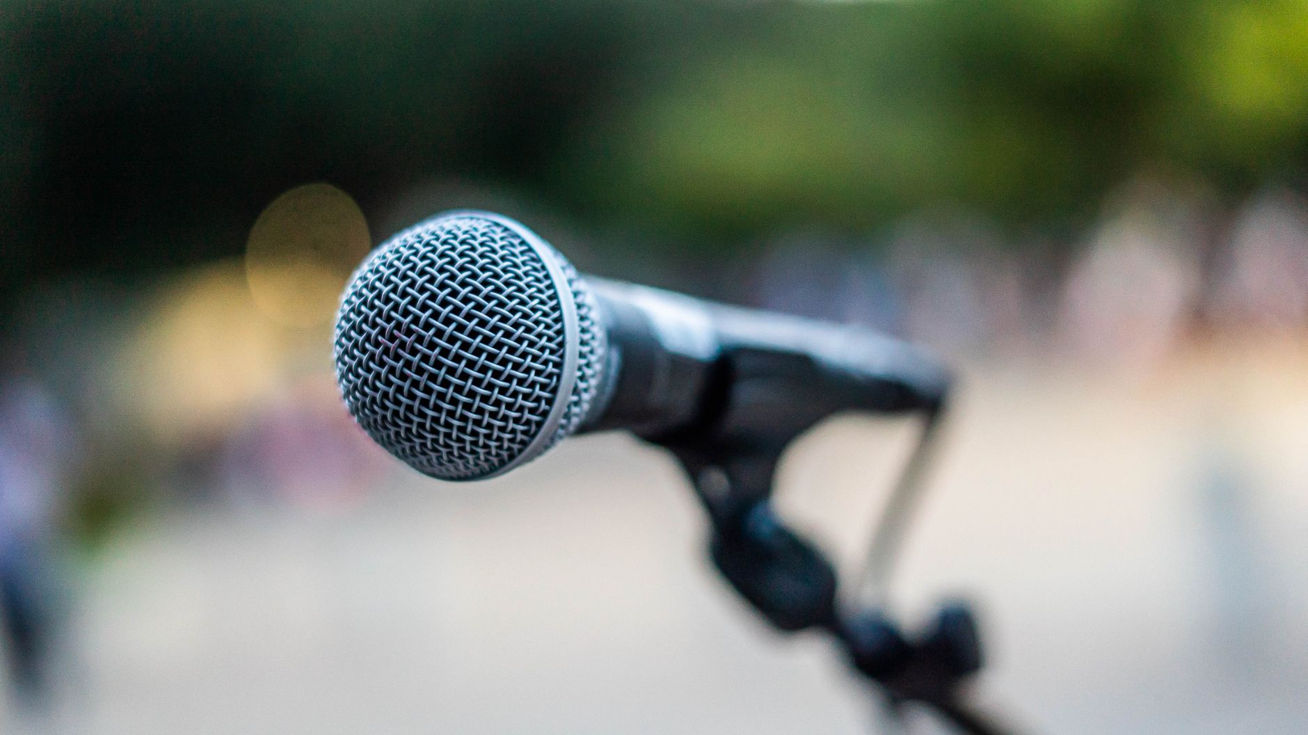 Soft focus of contemporary microphone on holder placed on stage during performance in park