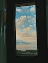 Countryside with fluffy clouds through window
