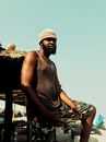 Black man standing near thatched roof