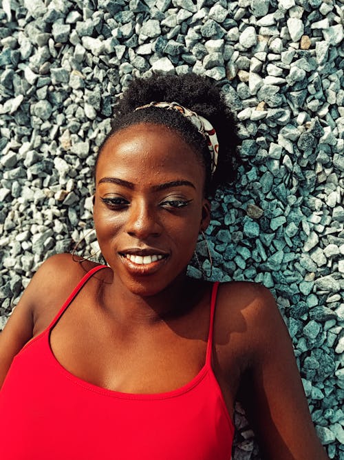 Free Cheerful black woman lying on stone beach Stock Photo