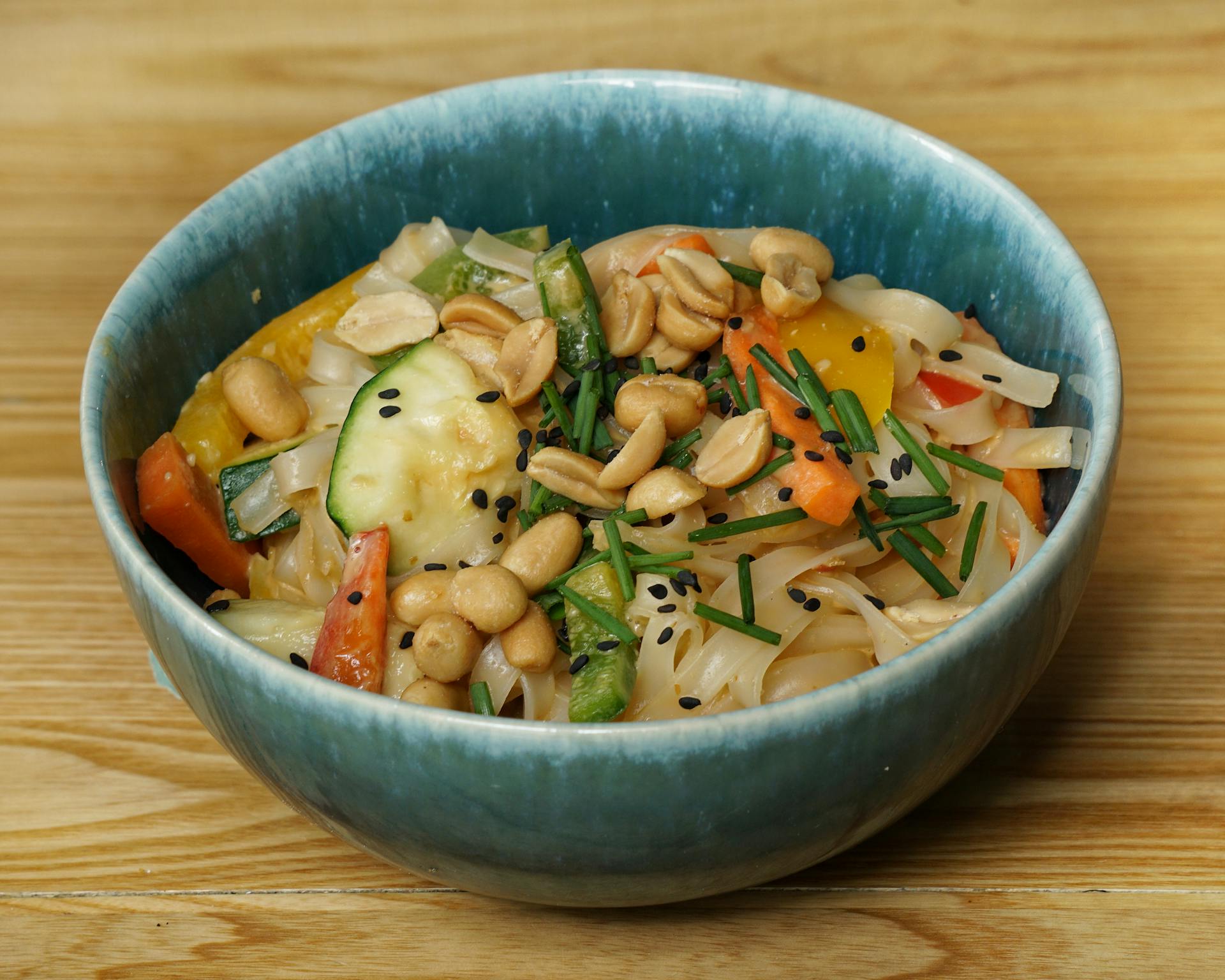 Colorful vegetable and peanut salad presented in a ceramic bowl.