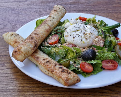 Vegetable Salad with Cheese on Top and Toasted Bread Stick on the Side