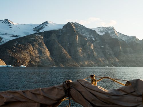 Free A breathtaking view of snow-capped mountains and rugged coastline at sunrise, showcasing pristine natural beauty. Stock Photo