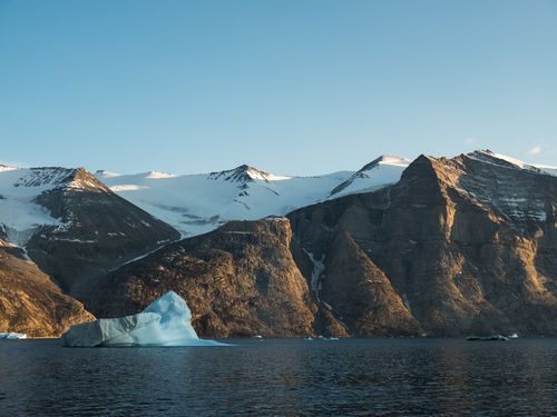 Free A breathtaking view of icy waters, snow-capped mountains, and icebergs in the Arctic region under a clear sky. Stock Photo