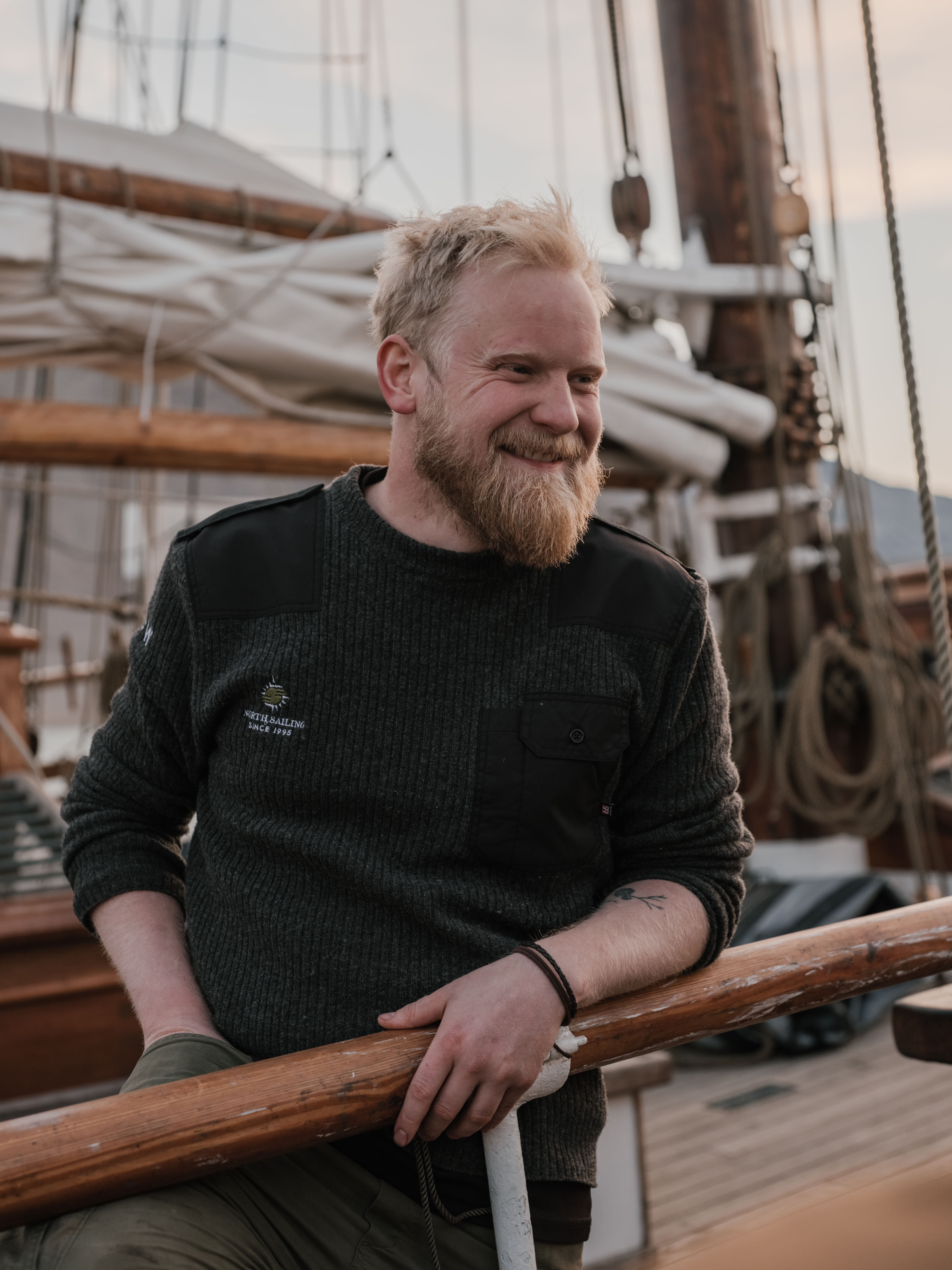 Bearded sailor enjoying leisure time on a sailboat. Calm and content atmosphere.