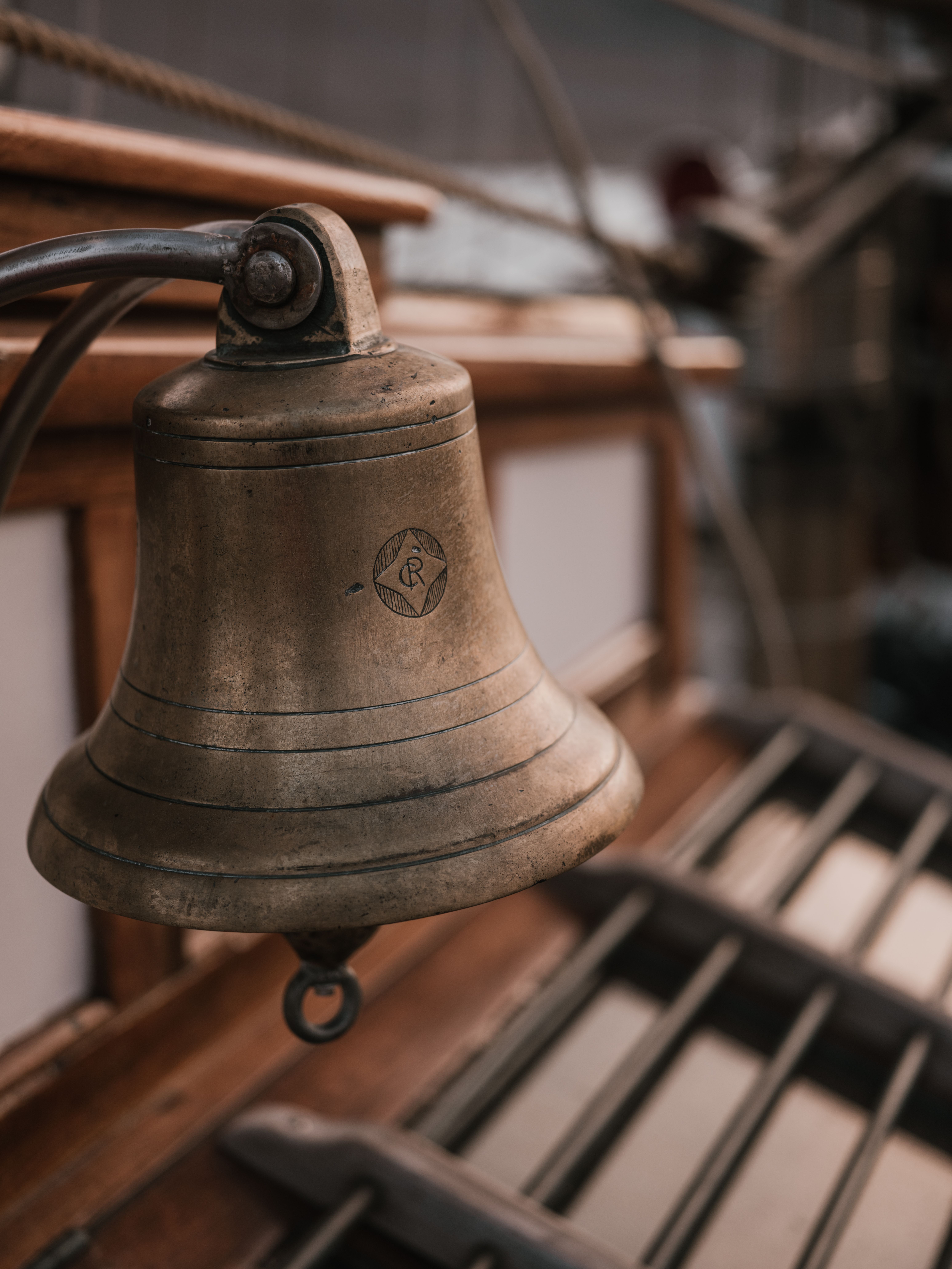 Captivating close-up of an antique brass nautical bell on a wooden ship deck, showcasing maritime history.