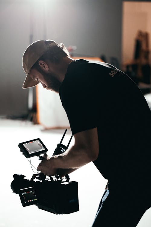 Man in Black Crew Neck T-shirt Holding Black Camera in the Studio