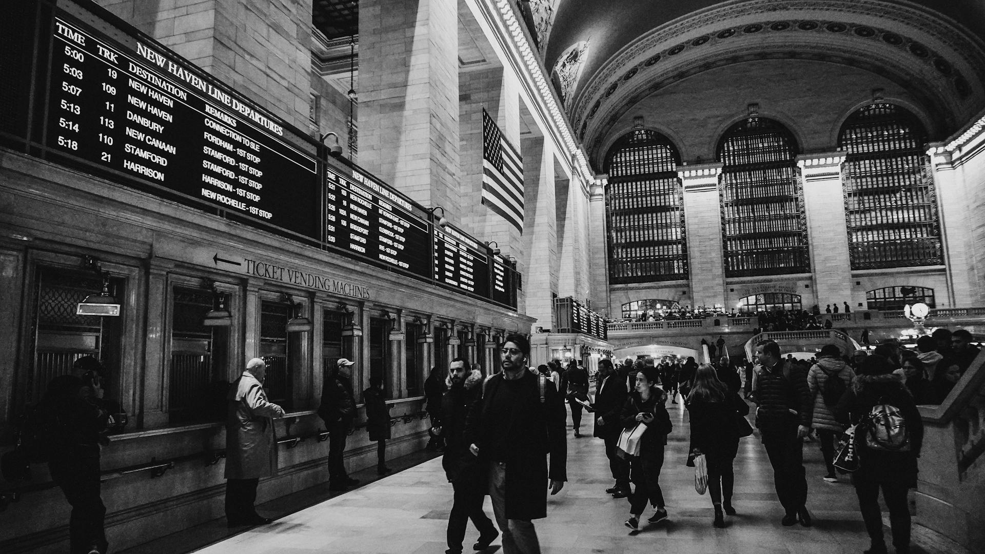 Black and white image of bustling Grand Central Terminal in New York City with commuters.