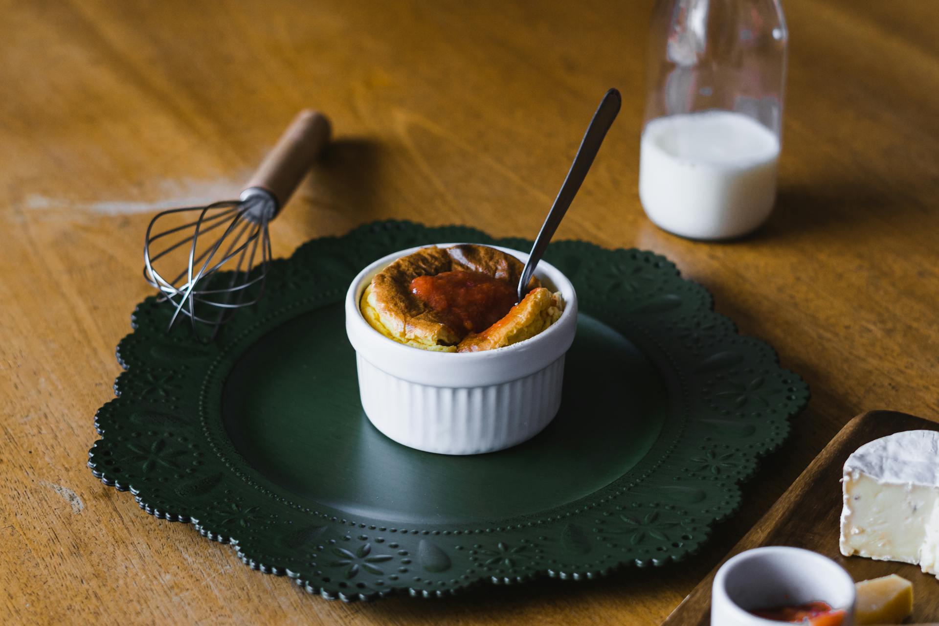 An appetizing soufflé served on a rustic plate with milk and cheese on a wooden table.