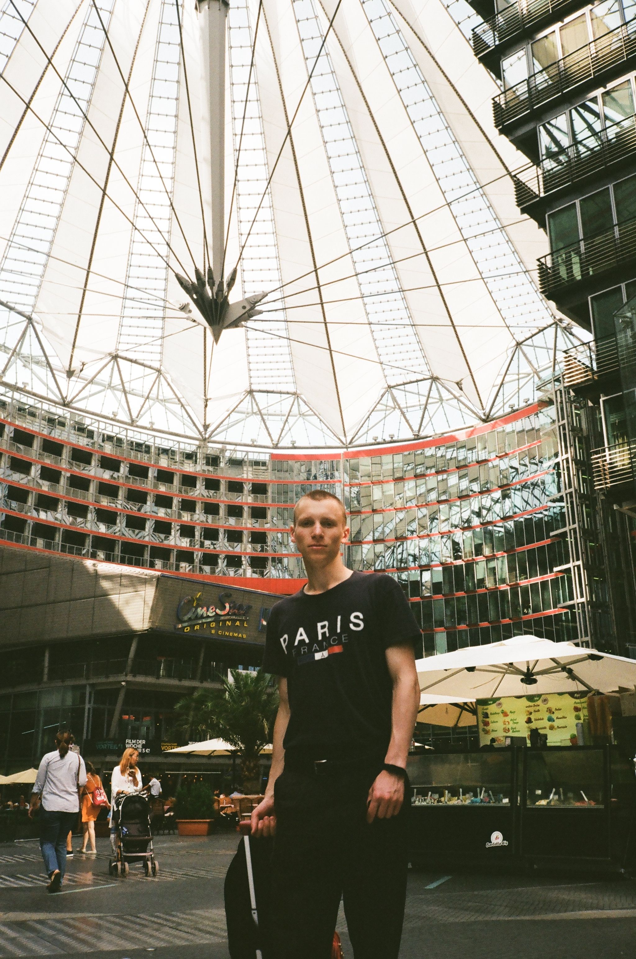 Low angle of young male traveler with rucksack standing on road near contemporary house exterior in city and looking at camera