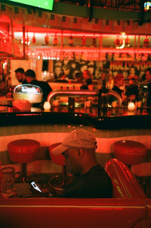 Free A person sitting at a retro diner bar, using a cellphone, with a classic Hollywood theme. Stock Photo