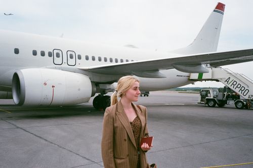Free Content blond female traveler in stylish apparel looking away on asphalt roadway near aircraft during trip Stock Photo
