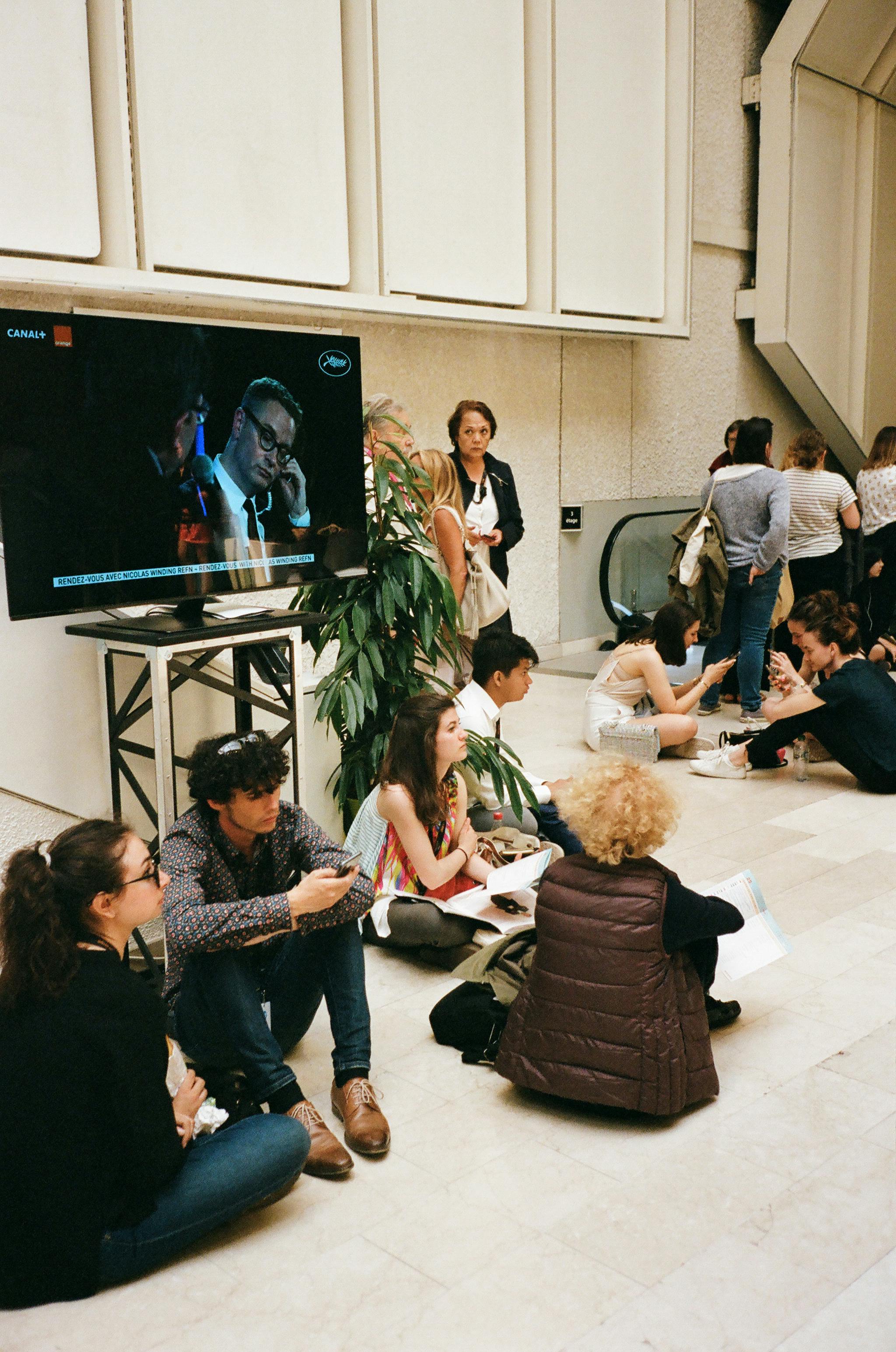 anonymous multiracial people on floor in hall with tv