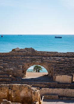 Capture the ancient charm of Tarragona's Roman amphitheatre with a stunning Mediterranean backdrop. Perfect for travel and history enthusiasts.
