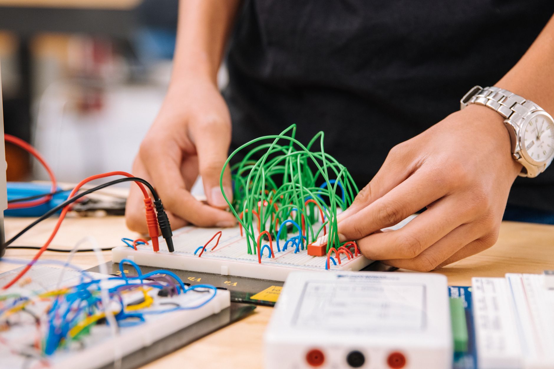 Gros plan des mains d'un technicien vérifiant les connexions des disjoncteurs dans un panneau électrique professionnel.