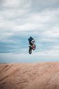 Anonymous sportsman riding enduro motorcycle in air