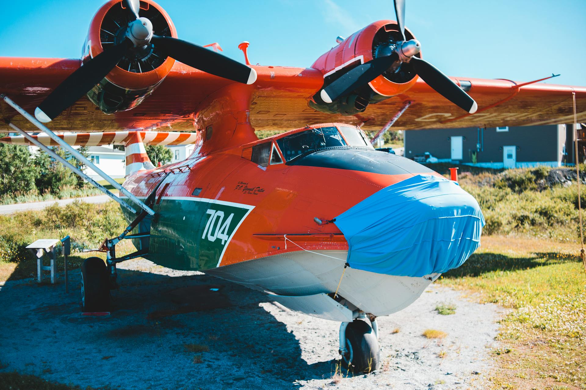 A brightly colored amphibious plane sits outdoors in clear daylight, showcasing its robust design.