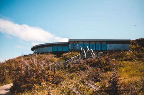Free From below of modern geometric building located on grassy hilltop against blue sky in countryside Stock Photo